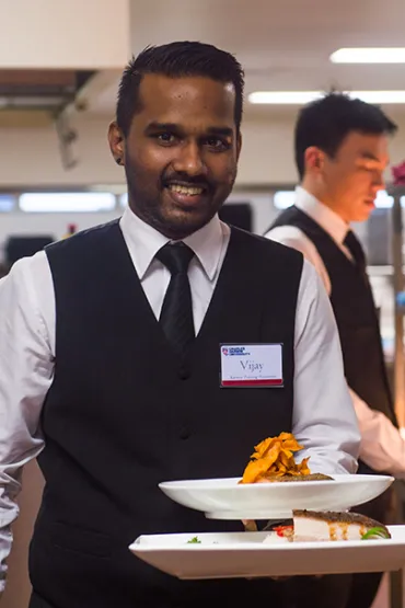 Student in training with a plate of food at Karawa Training Restaurant in Palmerston 